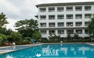 Baan Suan Lalana outdoor swimming pool with a slide and a white condo building surrounded by lush trees.