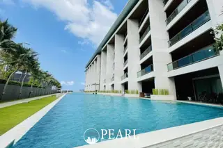 Ananya Beachfront Wongamat aerial view of long swimming pool, beachfront, ocean, and tropical landscaping.