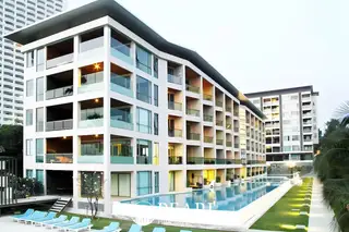 Ananya Beachfront Wongamat exterior of the modern condo building with a long swimming pool and lounge chairs.