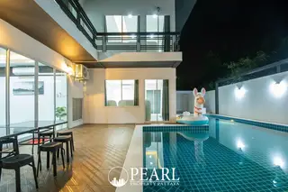 Baan Piam Mongkhon 3 modern house exterior at night with illuminated windows and a private swimming pool.