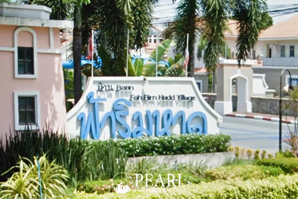 Fa Rim Haad Village entrance sign with blue Thai script, English text, and lush green landscaping.