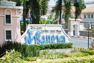 Fa Rim Haad Village entrance sign with blue Thai script, English text, and lush green landscaping.