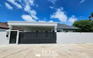 Hillside Village Pattaya modern house exterior from the street, featuring a white wall and a dark gate.