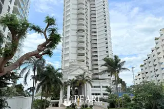 Sliver Beach close-up of the tall white condo building with many balconies, surrounded by palm trees and lush greenery.