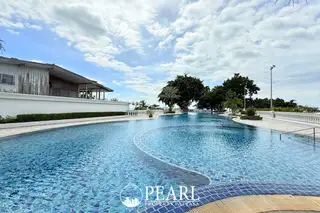 Sliver Beach large outdoor swimming pool with intricate blue tiling, surrounded by green landscaping and a building with a white facade.