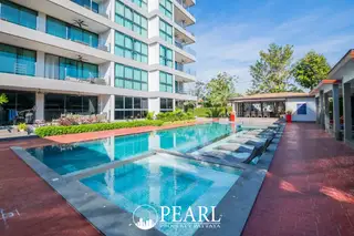 Serenity Residence Jomtien outdoor swimming pool area with lounge chairs and the apartment building in the background.