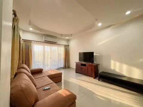 3 Bedroom House for Rent at PMC Home 4 living room with brown leather sofa, TV stand and curtained window