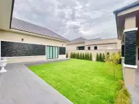 3 Bedroom House for Sale in Pong backyard view with manicured lawn, stone wall accents and tiled patio