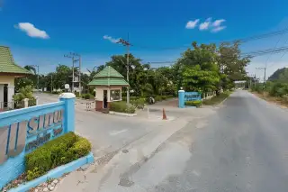 Ponthep Garden Ville 5 main entrance with security guard booth, blue signage, and tree-lined roads under a cloudy sky.