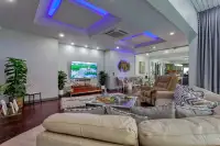 5 Bedroom House for Sale & Rent in Pratumnak Hill open-plan living room with blue LED coffered ceiling, leather sofa and wall-mounted TV