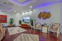5 Bedroom House for Sale & Rent in Pratumnak Hill lounge area with gold sculptural wall art, accent chairs, LED purple ceiling and large TV
