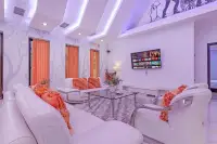 4 Bedroom House for Sale & Rent in Pratumnak Hill living room with white leather sofas, orange cushions, smart TV, and tree-print wallpaper