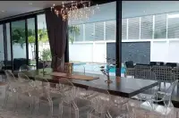 7 Bedroom House for Sale & Rent in Pratumnak Hill dining area with acrylic chairs, wood table and pool view through glass doors