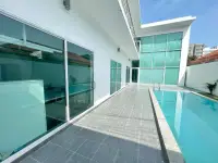 6 Bedroom House for Sale & Rent in Pratumnak Hill poolside walkway along glass doors and green facade
