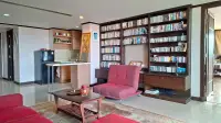 1 Bedroom Condo for Sale at Prime Suites lounge area with red armchair, built-in library shelves and kitchenette