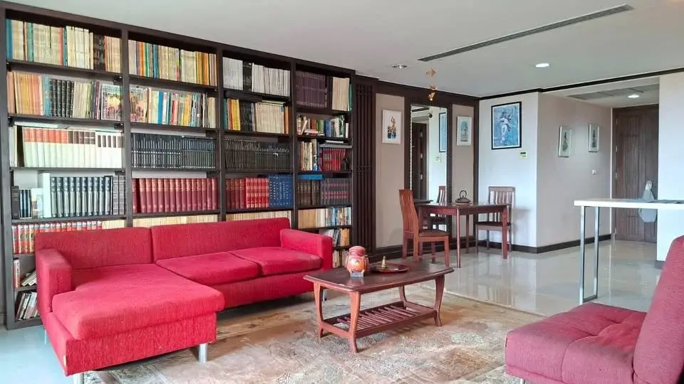 1 Bedroom Condo for Sale at Prime Suites living room with red sofas, floor-to-ceiling bookshelves and wood coffee table