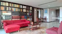 1 Bedroom Condo for Sale at Prime Suites living room with red sofas, floor-to-ceiling bookshelves and wood coffee table
