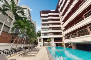 Prime Suites outdoor swimming pool with lounge chairs, surrounded by modern condo buildings and palm trees.