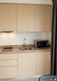1 Bedroom Condo for Sale at Sea Zen compact kitchen with wood cabinets, sink and microwave