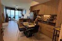 1 Bedroom Condo for Sale at Zire Wongamat open-plan kitchen with dining table and sea view living area.