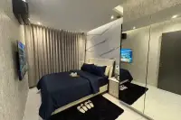 2 Bedroom Condo for Sale at Zenith Pattaya master bedroom with navy blue bedding, marble feature wall, and mirrored wardrobe