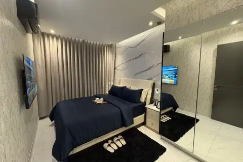 2 Bedroom Condo for Sale at Zenith Pattaya bedroom with navy bedding, mirrored closet, and wall-mounted TV