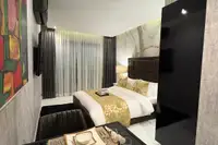 Studio Condo for Sale at Grand Solaire Noble: Bedroom with a large bed, window curtains, and a glimpse of the dining area.