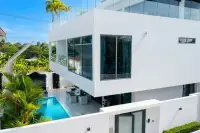 8 Bedroom House for Sale in Pratumnak Hill modern white exterior with glass balcony, pool, and lush landscaping
