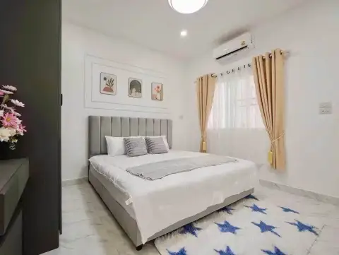 4 Bedroom House for Sale at Raviporn City Home bedroom with gray upholstered bed and tan curtains