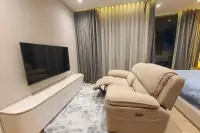 1 Bedroom Condo for Sale & Rent at Arom Wongamat bedroom seating area with recliner sofa, large TV on white marble console, and floor-to-ceiling curtains
