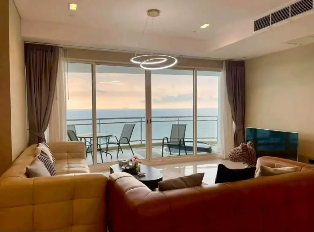 3 Bedroom Condo for Rent at Reflection Jomtien Beach living room with leather sofas and panoramic sea view balcony