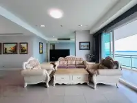 3 Bedroom Condo for Sale at Reflection Jomtien Beach spacious living area with classic furniture and sea-view balcony