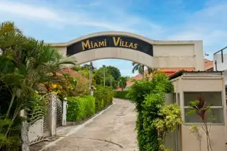 Miami Villas gated entrance archway with lush tropical greenery and palm trees in Pattaya Thailand