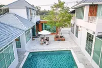 10 Bedroom House for Sale in Na Chom Thian: Aerial view of courtyard with pool, two people under umbrella, and multiple buildings.