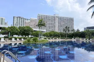 Rimhad Jomtien Condominium S2 swimming pool with tropical garden and city skyline backdrop