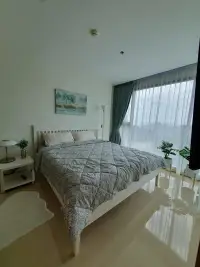 2 Bedroom Condo for Sale at The Riviera Jomtien master bedroom with white bed frame and sheer curtains overlooking city
