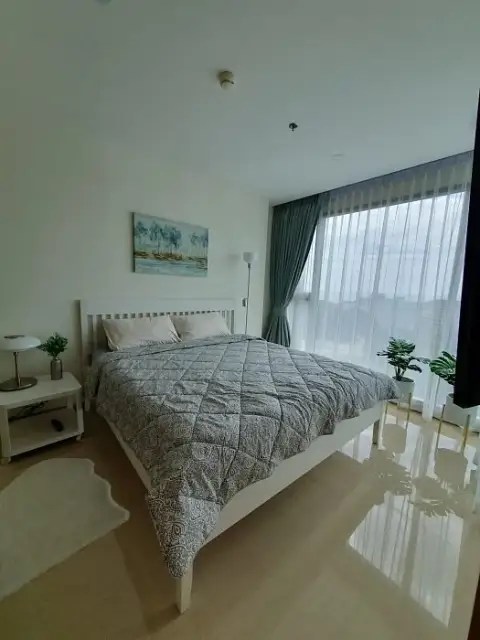 2 Bedroom Condo for Sale at The Riviera Jomtien master bedroom with white bed frame and sheer curtains overlooking city