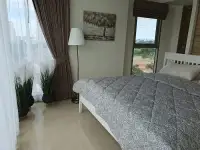 2 Bedroom Condo for Sale at The Riviera Jomtien second bedroom with gray bedding and window view of Pattaya