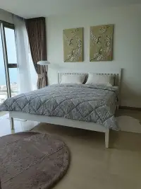 2 Bedroom Condo for Sale at The Riviera Jomtien bedroom with white bed frame and floral wall art