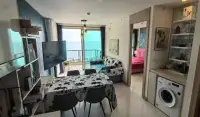 1 Bedroom Condo for Sale at The Riviera Jomtien open-plan living room with sea view balcony and pink bedroom visible
