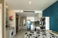 1 Bedroom Condo for Sale at The Riviera Jomtien kitchen with white cabinetry, fridge, and dining table setup