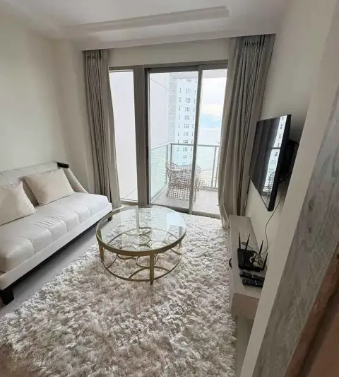 1 Bedroom Condo for Rent at Riviera Monaco lounge area with plush rug, glass coffee table and balcony view