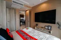 1 Bedroom Condo for Sale at Riviera Monaco bedroom with large TV, wall mirror, and red accent bedding