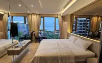 2 Bedroom Condo for Sale & Rent at Riviera Monaco master bedroom with king bed, mirrored wall and sea view through floor-to-ceiling windows