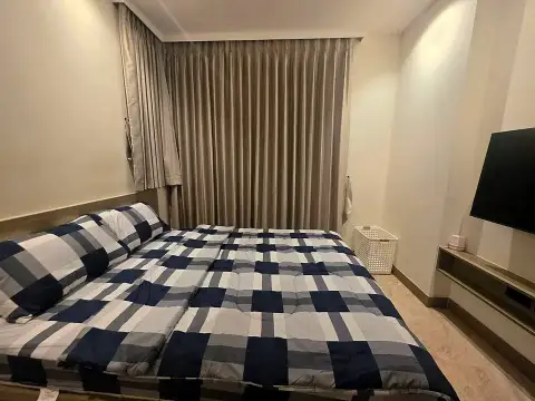 1 Bedroom Condo for Rent at Riviera Ocean Drive bedroom with plaid comforter and wall-mounted TV