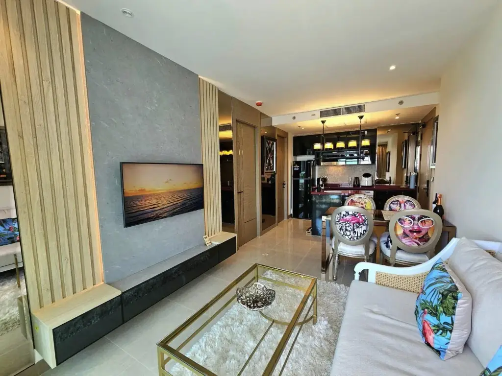 1 Bedroom Condo for Rent at Riviera Ocean Drive living room with wall-mounted TV and dining area with artistic chairs