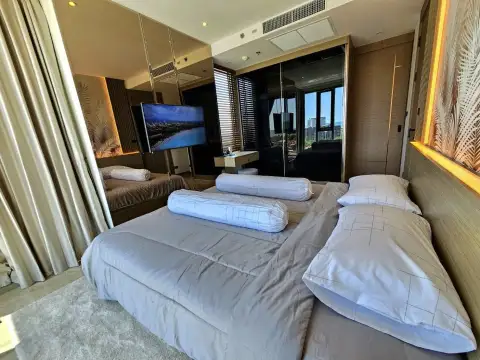 1 Bedroom Condo for Rent at Riviera Ocean Drive bedroom with mirrored wardrobe, TV, and wooden window blinds