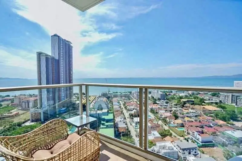 2 Bedroom Condo for Sale at Riviera Ocean Drive balcony view with rattan chairs overlooking Pattaya skyline and sea