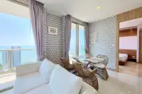 2 Bedroom Condo for Rent at Riviera Wong Amat Beach bright living and dining space with white sofa, sea view balcony, and bedroom entrance