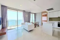 2 Bedroom Condo for Rent at Riviera Wong Amat Beach open-plan living room with white sofa, dining area, and floor-to-ceiling sea view windows